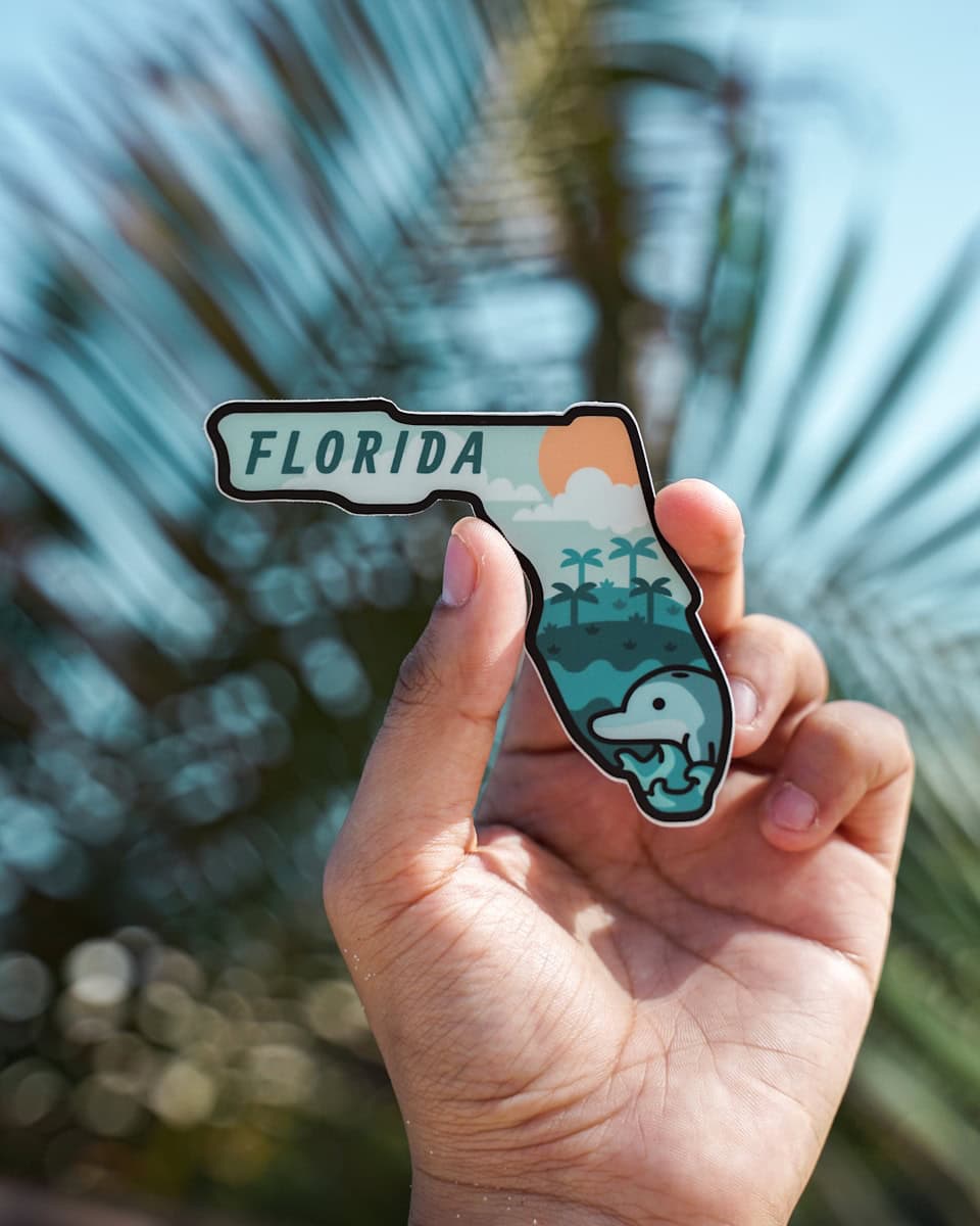 person holding white and black Florida sticker